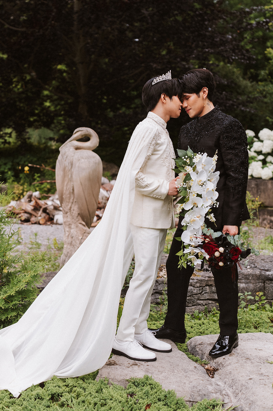 James and Andrew forehead to forehead in a garden before their ceremony