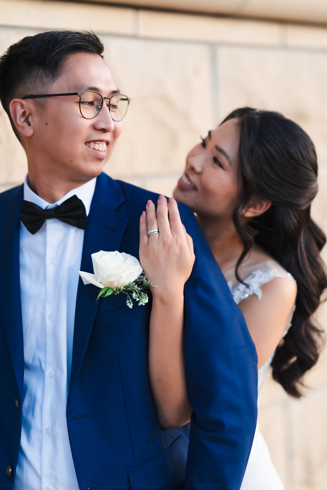 Monica resting her hand on Andrew's lapel, her wedding ring in frame